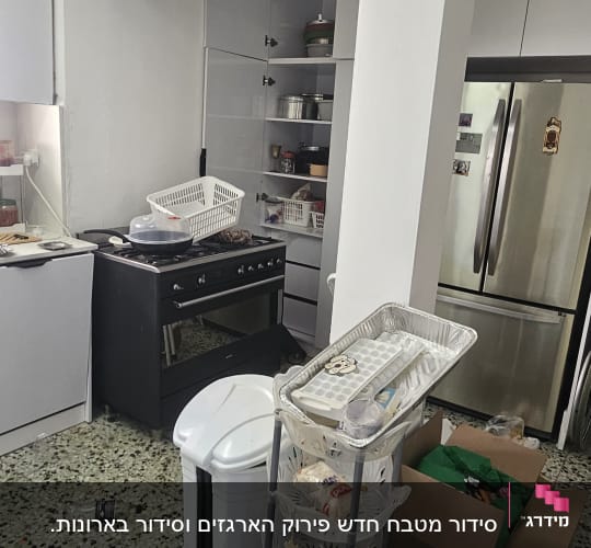 מטבח עם מדפים פתוחים, עגלת אחסון, שקיות וקרטון.